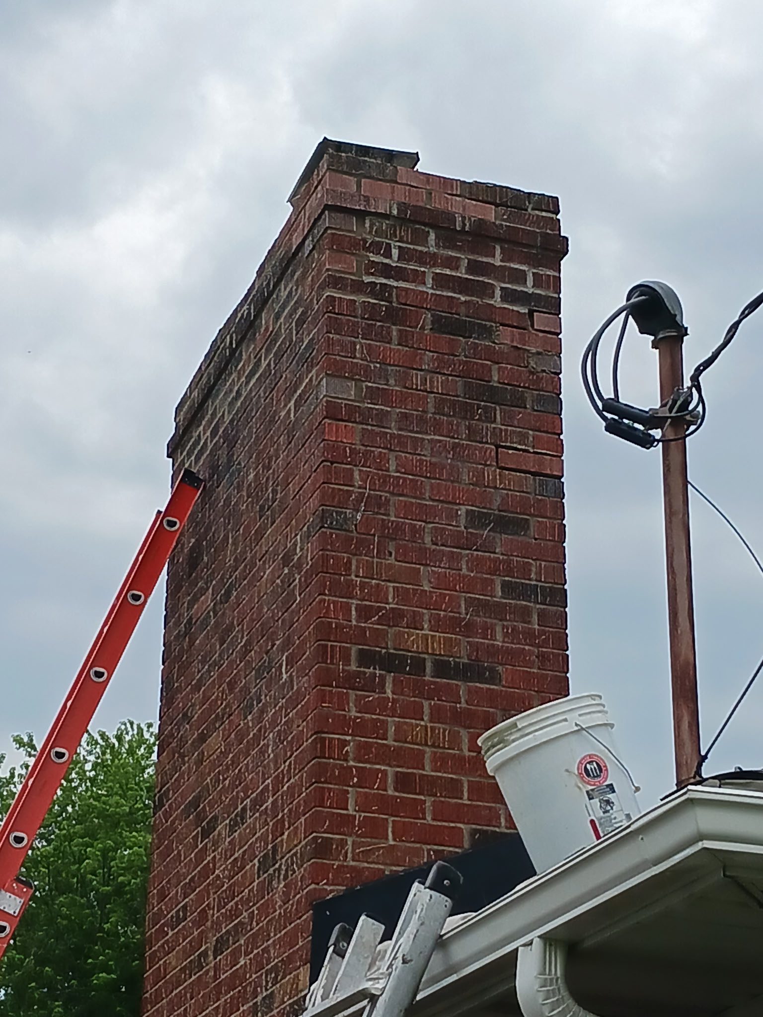 Brick chimney with ladder and bucket nearby.