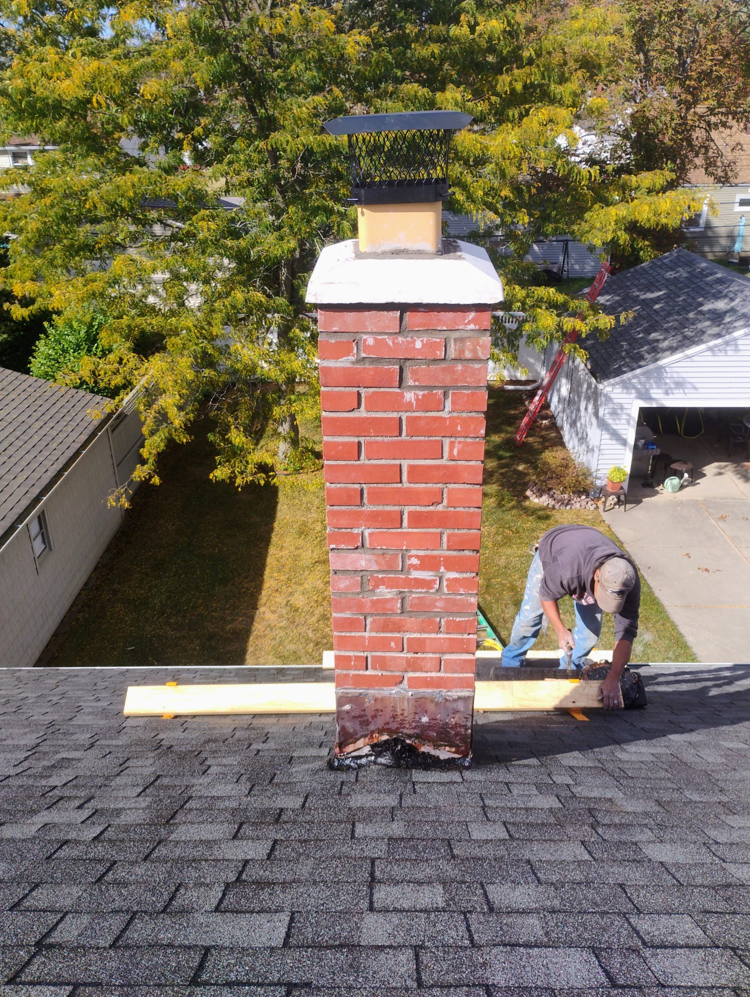 Man working on roof near brick chimney.