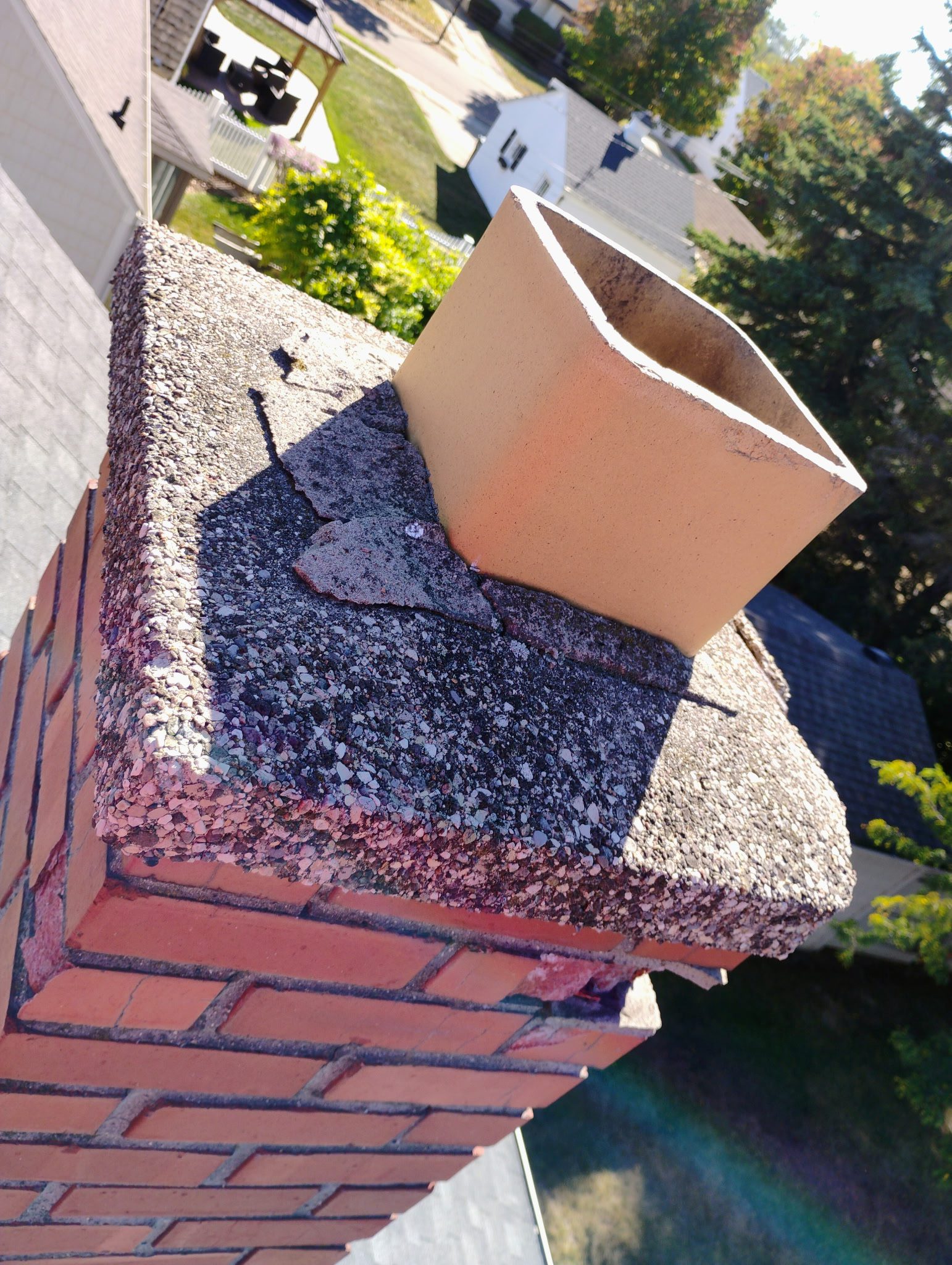 Brick chimney with damaged concrete top.