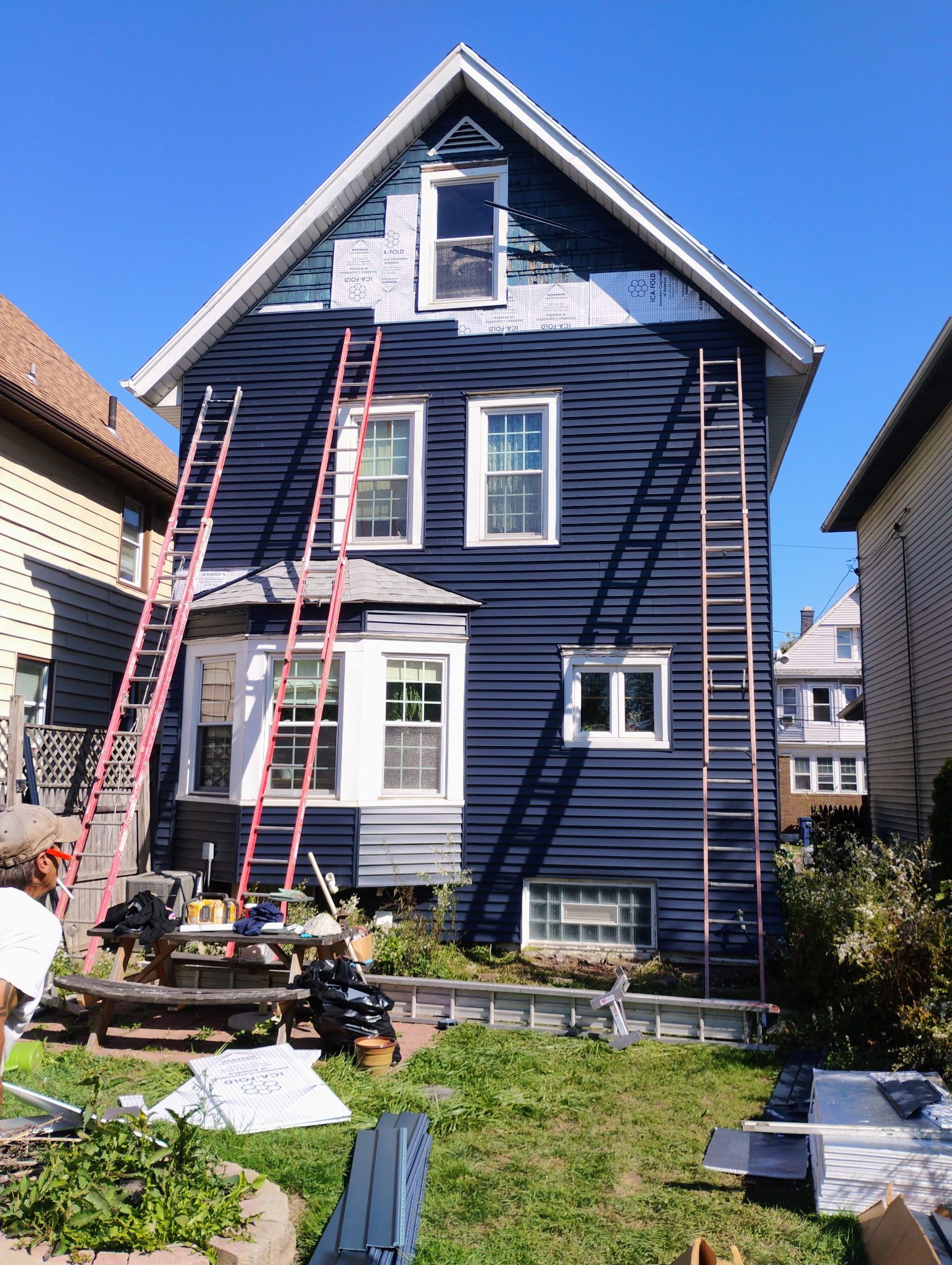 Blue house under renovation with ladders outside.