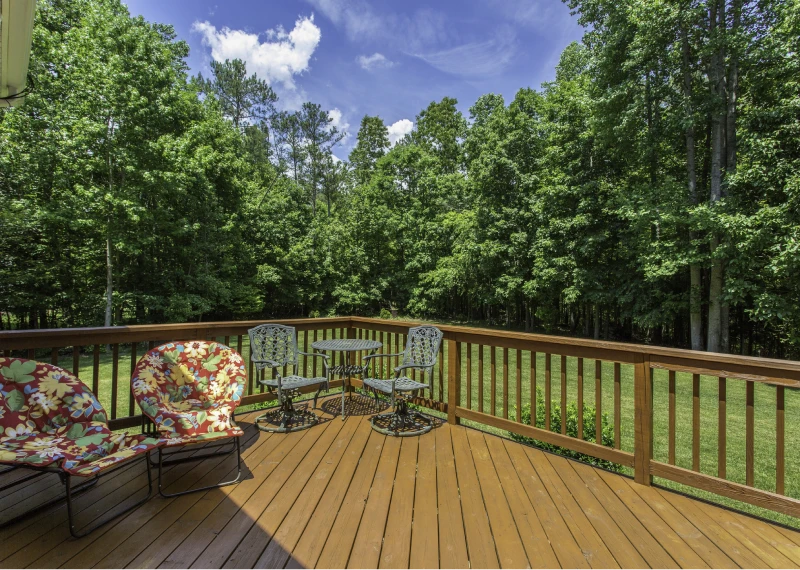 Wooden deck with chairs and forest view.