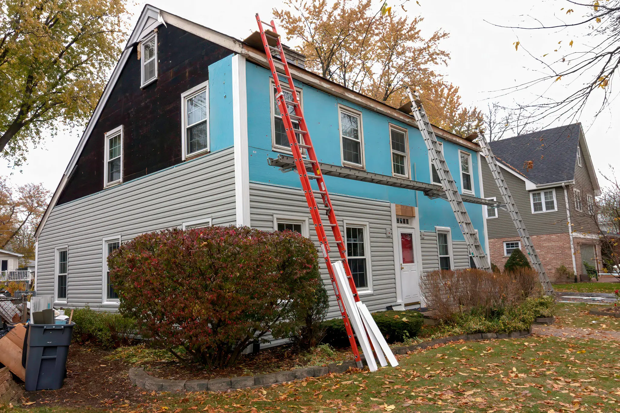 House exterior renovation with ladders and scaffolding.